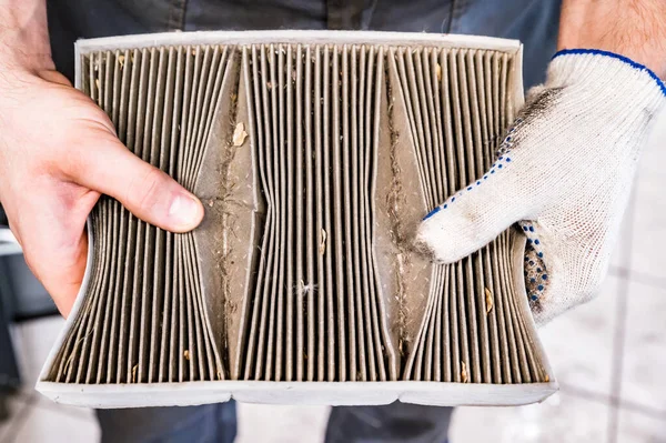 Hand van mechanik is houdt oude auto luchtfilter Stockfoto