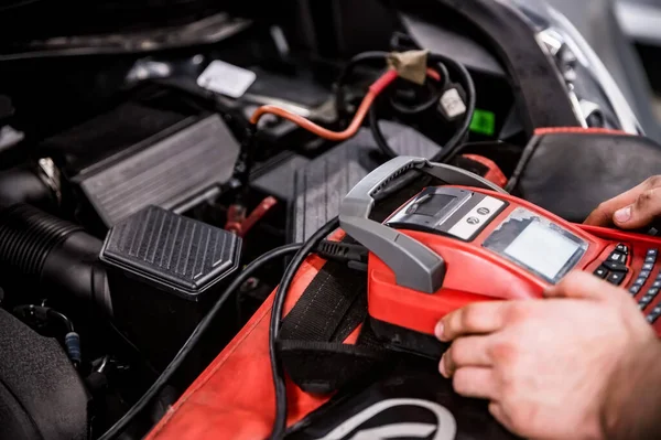 汽车修理工的手检查汽车电池充电 免版税图库图片