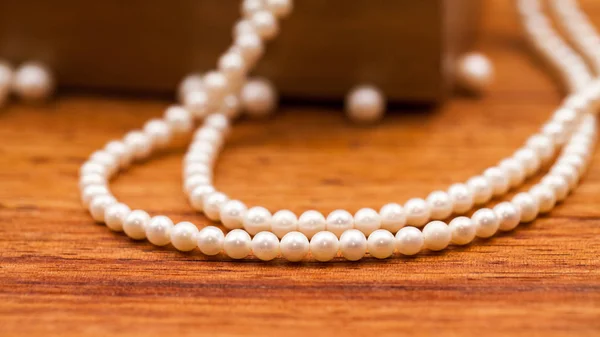 白色珍珠珠在模糊的木制背景与胸部 — 图库照片