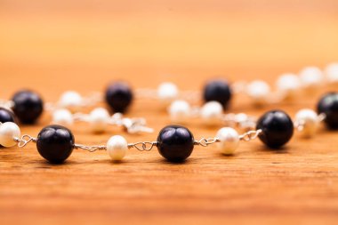 Ahşap arka plan üzerinde zincir ile şık siyah ve beyaz boncuklar