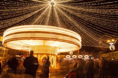 24 Aralık 2014 Sibiu, Romanya. Noel ışıkları, atlıkarınca taşıma, Noel Fuarı, ruh hali ve mavi saatinde dolaşan insanlar