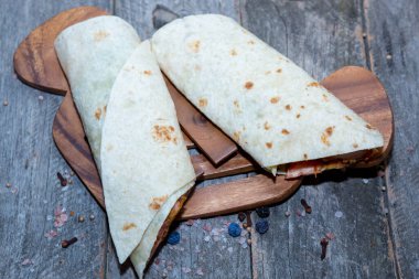 Tahta yüzeyde sebzeli tavuk dürümü.