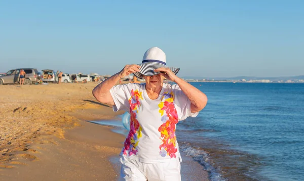 Yaşlı bir kadın deniz kıyısında yürüyor..