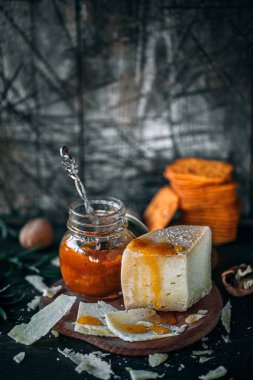 Rustik koyu arka plan üzerinde kayısı reçelli sert peynir