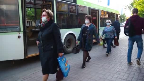 Las personas con máscaras protectoras salen del transporte público en la parada de autobús. Proteger a los pasajeros del coronavirus. estilo de vida durante la pandemia. Nueva normalidad. Volgodonsk, Rusia-25 de junio de 2020 . — Vídeo de stock