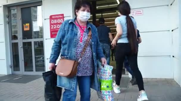 Mulher idosa com máscara protetora sai do supermercado com bolsas. Compra de produtos. Vida durante a pandemia do coronavírus. Medidas de protecção e prevenção. Rússia, Volgodonsk 25 de junho de 2020 . — Vídeo de Stock