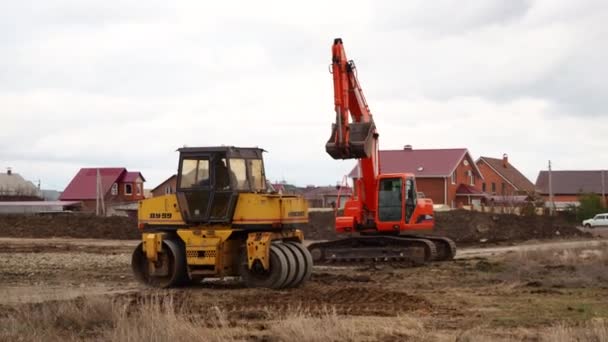 Crawler loader gravemaskine, bulldozer og rulle arbejde på byggepladsen. Maskiner udfører udgravningsarbejde. Komprimering af jord og murbrokker til beboelsesejendomme. Volgodonsk, Rusland 10 marts 2020. – Stock-video