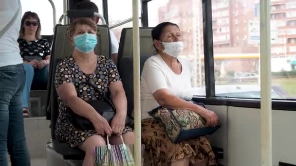 Duas mulheres adultas em máscaras de proteção andam de transportes públicos pela cidade em um dia de verão. Pessoas e distância social. Passageiros de ônibus estão protegidos contra coronavírus. Nova norma. modo de vida durante a pandemia . — Vídeo de Stock