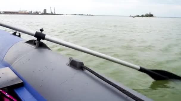 Une rame fixée sur le côté d'un bateau pneumatique en caoutchouc flottant à vitesse. Main masculine d'un pêcheur ramant sur la rivière. Un fragment de gros plan. — Video