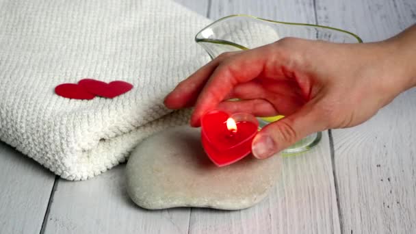 Концепція "Спа на Валентинів день". Дівчина - косметолог запалює свічки у формі червоного серця. Підготовка офісу до сеансів відпочинку та благополуччя. Процедура купання, косметологія — стокове відео