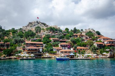 Dağda şatosu olan antik Simena köyü. Tekne iskelesi, güzel manzara. Demre yakınlarındaki Kekova adasında Lycian sualtı şehri deniz turu. Antalya Eyaleti. Kalekoy, Türkiye