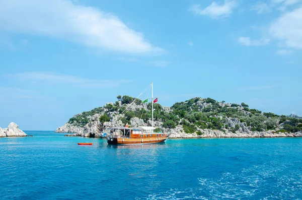 Tourist ship on the background of a beautiful summer mountain landscape on the Mediterranean sea. Excursion to Turkey. Sea tour of the historical monument of architecture. People on vacation. — Stock Photo, Image