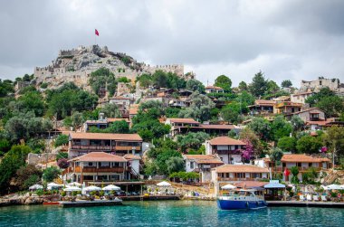 Dağda şatosu olan antik Simena köyü. Tekne iskelesi, güzel manzara. Demre yakınlarındaki Kekova adasında Lycian sualtı şehri deniz turu. Antalya vilayeti. Kalekoy, Türkiye