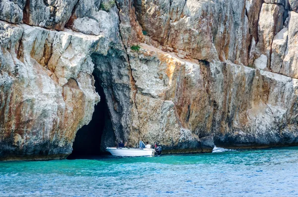 Malá turistická motorová loď s turisty na pozadí rokle. Vstup do velké jeskyně v horách Středozemního moře. Prohlídka okolí provincie Antalya. Kemer, Turecko 11. června 2018. — Stock fotografie