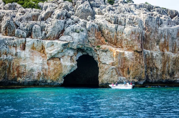 以峡谷为背景的带游客的小型观光汽艇.地中海山脉的一个大洞穴的入口。参观安塔利亚省周边地区。2018年6月11日，土耳其凯末尔. — 图库照片