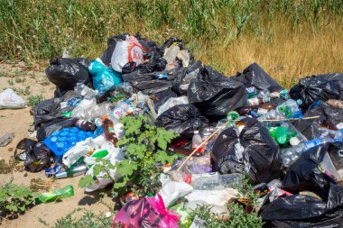 Nehir kıyısına dök. Doğadaki çöpler. Bir sürü siyah çöp torbası. Çevresel kirlilik sorunu. Büyük bir şehirde katı atık imhası. Volgodonsk, Rusya 07 Mart 2020.