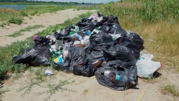 Vyhoďte to na břeh řeky. Odpadky v přírodě. Spousta černých pytlů s odpadem. Environmentální problém znečištění životního prostředí. Pevná likvidace odpadu ve velkém městě. Volgodonsk, Rusko 7. března 2020. — Stock video