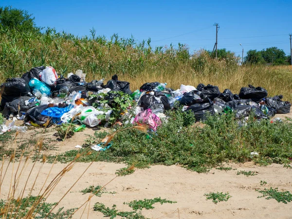 Nehir kıyısına dök. Doğadaki çöpler. Bir sürü siyah çöp torbası. Çevresel kirlilik sorunu. Büyük bir şehirde katı atık imhası. Volgodonsk, Rusya 07 Mart 2020.
