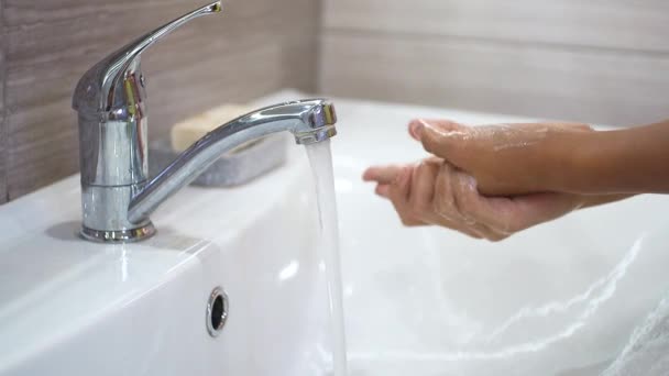 Teenager washes his hands with soap under a stream of water in sink. Clean your hands to prevent spread of bacteria and viral infection. Protecting children during a pandemic. Hygiene and cleanliness. — Stock Video