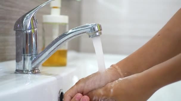 Teenager si lava le mani con il sapone sotto un flusso d'acqua nel lavandino. Pulire le mani per prevenire la diffusione di batteri e infezioni virali. Proteggere i bambini durante una pandemia. Igiene e pulizia. — Video Stock