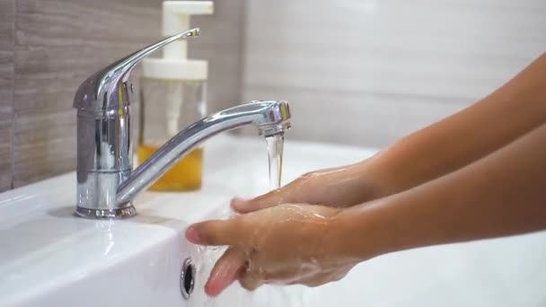 Un adolescente si lava le mani con il sapone sotto l'acqua corrente nel lavandino e poi chiude il rubinetto. Pulire le mani per prevenire la diffusione di batteri e infezioni virali. Proteggere durante una pandemia. — Video Stock