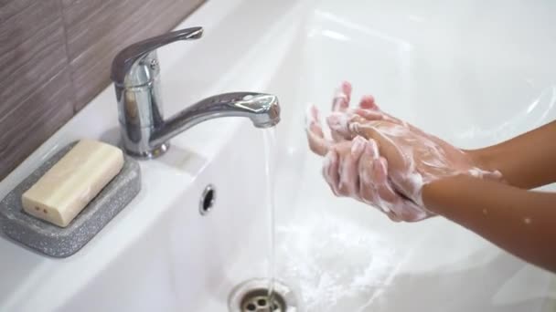 Teenager si lava accuratamente le mani con abbondanti saponette sotto un flusso d'acqua nel lavandino. Pulire le mani per prevenire la diffusione di batteri e infezioni virali. Proteggere i bambini durante una pandemia. — Video Stock
