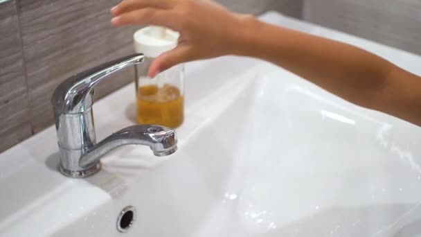 Un bambino piccolo si accende il rubinetto e si lava le mani con il sapone sotto l'acqua corrente nel lavandino. Pulire le mani per prevenire la diffusione di batteri e infezioni virali. Proteggere i bambini durante una pandemia. — Video Stock