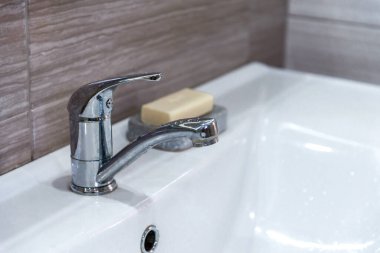İç kısımda beyaz lavabo ve modern metal ekonomik su musluğu var. Su tasarrufu. El yıkama ve hijyen için sabun. Bakteri ve viral enfeksiyonun yayılmasını önler. Boşluğu kopyala.