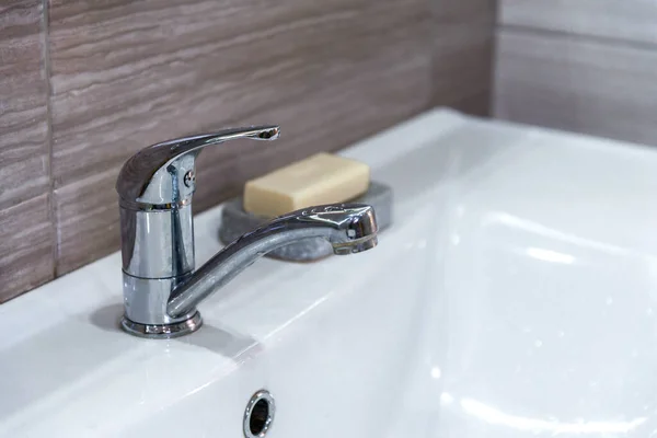 Lavabo bianco e moderno rubinetto in metallo economico all'interno. Risparmio idrico. Sapone per il lavaggio e l'igiene delle mani. Prevenire la diffusione di batteri e infezioni virali. Copia spazio. — Foto Stock