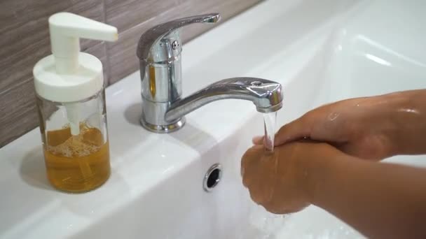 Dospívající dítě si umyje ruce mýdlem pod tekoucí vodou v umyvadle a pak vypne kohoutek. Umyjte si ruce, aby se zabránilo šíření bakterií a virové infekce. Ochrana během pandemie. — Stock video