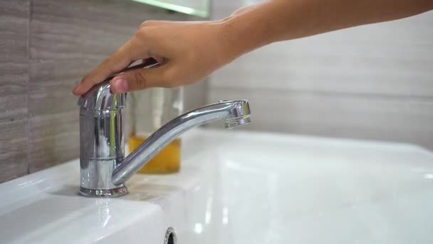 Un adolescente apre il rubinetto e si lava le mani con il sapone sotto l'acqua corrente nel lavandino. Pulisci le mani per prevenire la diffusione di batteri e infezioni virali. Proteggere i bambini durante una pandemia. — Video Stock