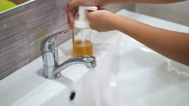 Un bambino adolescente si lava accuratamente le mani con il sapone sotto l'acqua corrente nel lavandino. Pulisci le mani per prevenire la diffusione di batteri e infezioni virali. Proteggere i bambini durante una pandemia. — Video Stock