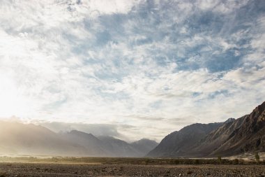 Hindistan 'ın Nubra Vadisi' nde, Leh Ladakh 'ta gündoğumu arka planında çarpıcı bir ışık ve güzel bir sis var. Lens alevli ışık manzarası.