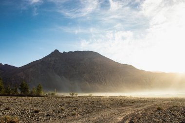 Hindistan 'ın Nubra Vadisi' nde, Leh Ladakh 'ta gündoğumu arka planında çarpıcı bir ışık ve güzel bir sis var. Lens alevli ışık manzarası.