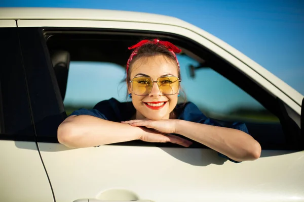 Car woman on road on road trip waving happy smiling out the window.