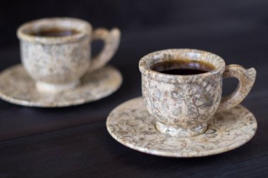 Ahşap arka plan üzerinde lezzetli kahve ile iki doğal jasper taş bardak.