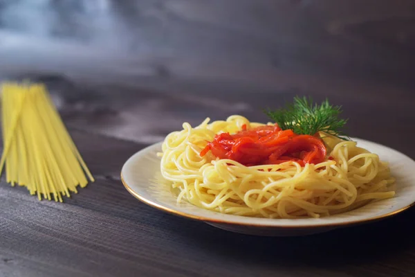 Ahşap bir masa üzerinde bir tabak içinde domates soslu makarna
