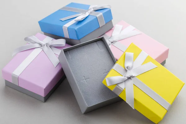 Small colorful jewelry gift boxes with bows on gray background. Present boxes for jewelry set