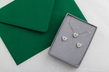 Gri hediye kutusunda yeşil zarf Pırlantalı kalp Kolye ve stud küpe takı seti. Uzay kopyalayın. Düğün, Sevgililer günü, yılbaşı ya da romantik fırsat için hediye fikri
