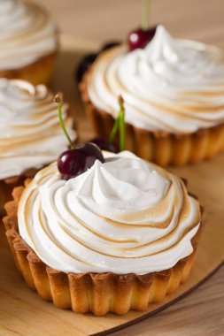 İtalyan beze ve taze kiraz tatlı meyve tartlets. Ahşap plat üzerinde tatlı mini tart