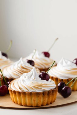 İtalyan beze ve taze kiraz tatlı meyve tartlets. Ahşap plat üzerinde tatlı mini tart