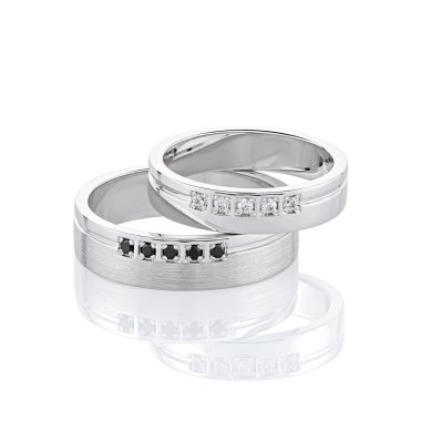 Beyaz arkaplanda elmaslarla izole edilmiş bir çift beyaz altın alyans. Siyah ve beyaz değerli taşlı orijinal gümüş alyans.