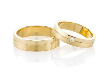 Beyaz arka planda izole edilmiş bir çift altın alyans. Sarı altın yüzük bantları birleşik parlak ve desenli yüzey