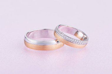 Pembe arka planda elmasları olan eşsiz alyanslar. Parlak ve dokulu yüzüklerle alyanslar.