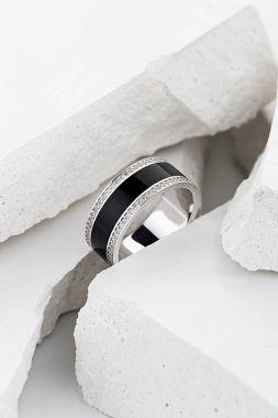 Beyaz arkaplanda elmaslarla süslenmiş siyah dişli gümüş alyans. Eşsiz tasarım düğün takıları. Mücevher reklamı hala hayat dolu