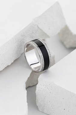 Beyaz arkaplanda elmaslarla süslenmiş siyah dişli gümüş alyans. Eşsiz tasarım düğün takıları. Mücevher reklamı hala hayat dolu