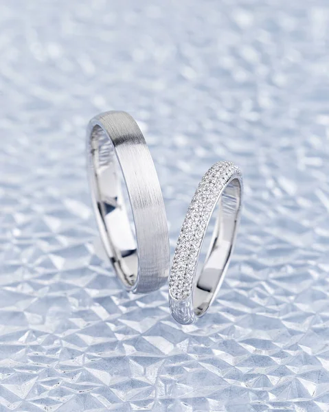灰色背景上的银婚戒指搭配 白色金戒指带与钻石在女性戒指上 并在男性戒指上的纹理表面 珠宝广告静谧生命 — 图库照片