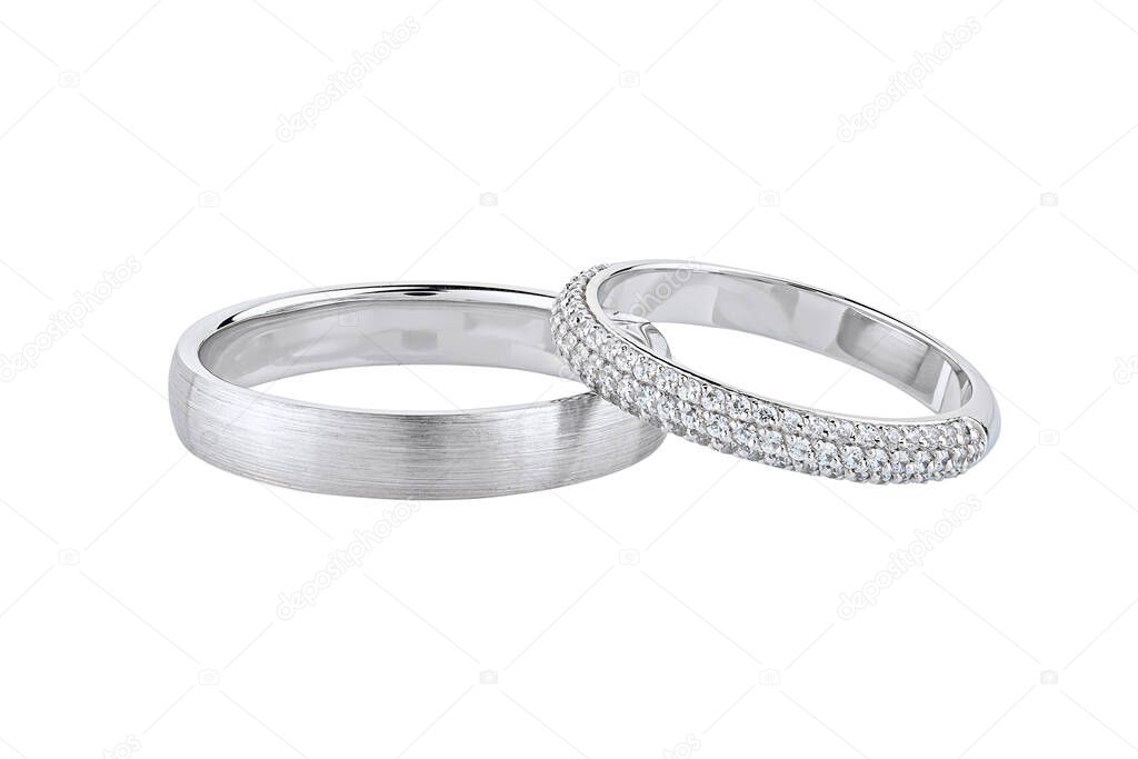 Pair of silver wedding rings isolated on white background. White gold ring bands with diamonds on female ring and matte textured surface on male ring