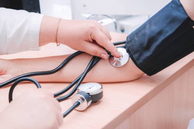 Hemşire, doktor ya da sağlık uzmanı hastanın kan basıncını elde taşınabilir tonometre yatay yakın çekim fotoğrafıyla ölçer.