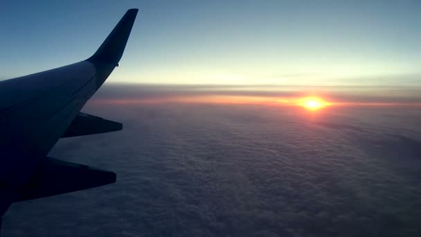 Puesta de sol sobre las nubes a través de la ventana de un avión — Vídeos de Stock